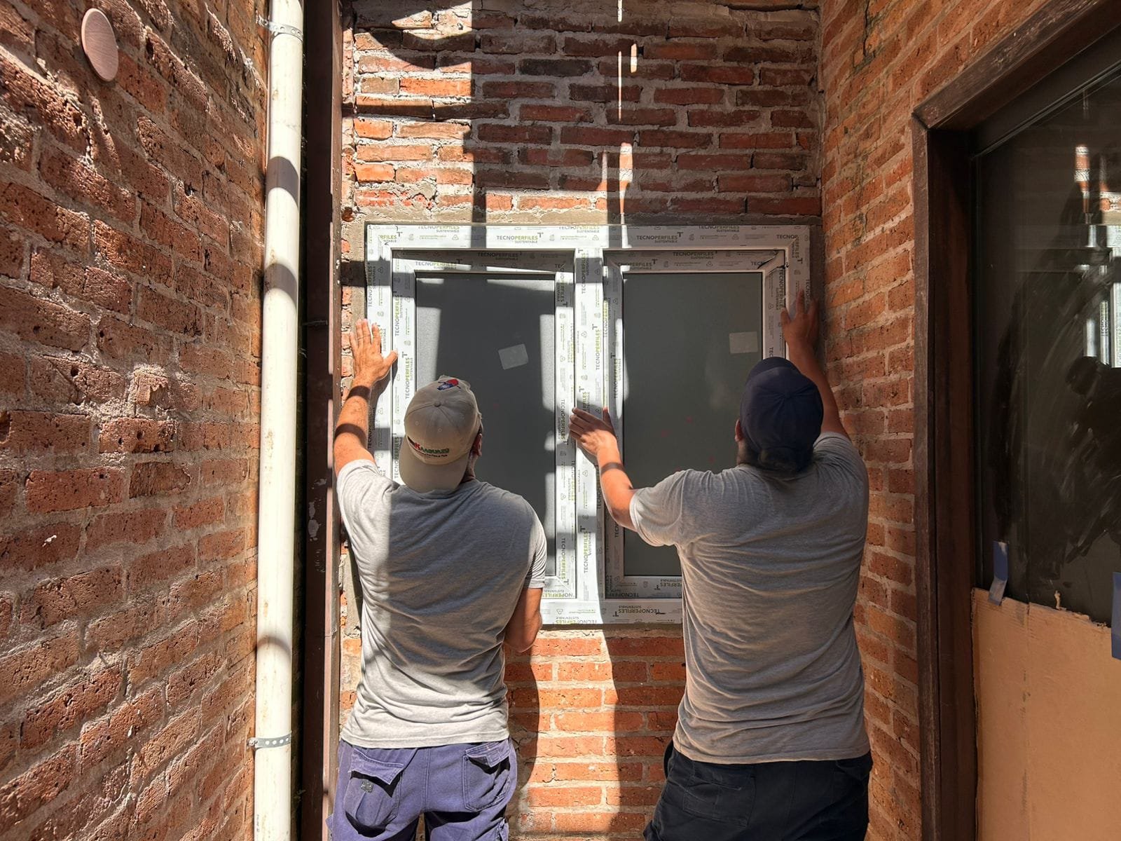 Instaladores de MÁS VIDRIOS colocando una ventana en obra