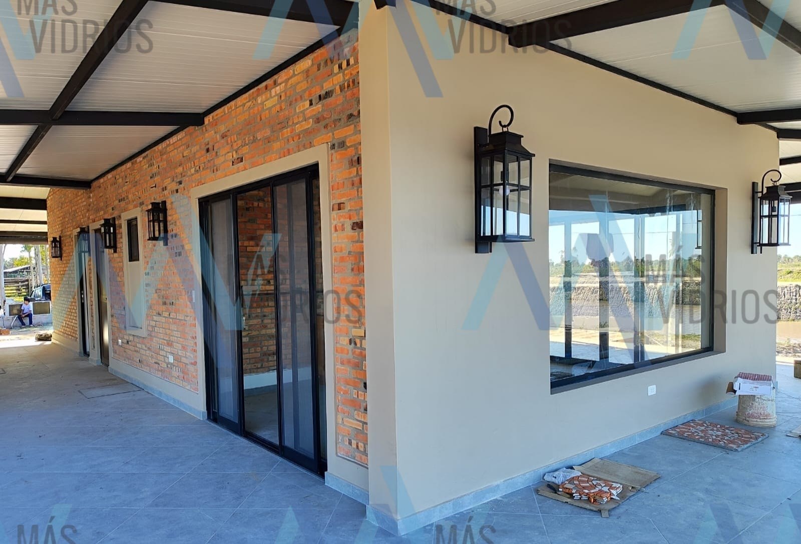 Puerta corrediza y ventana de aluminio negro en la galería de una casa de ladrillo visto · MÁS VIDRIOS