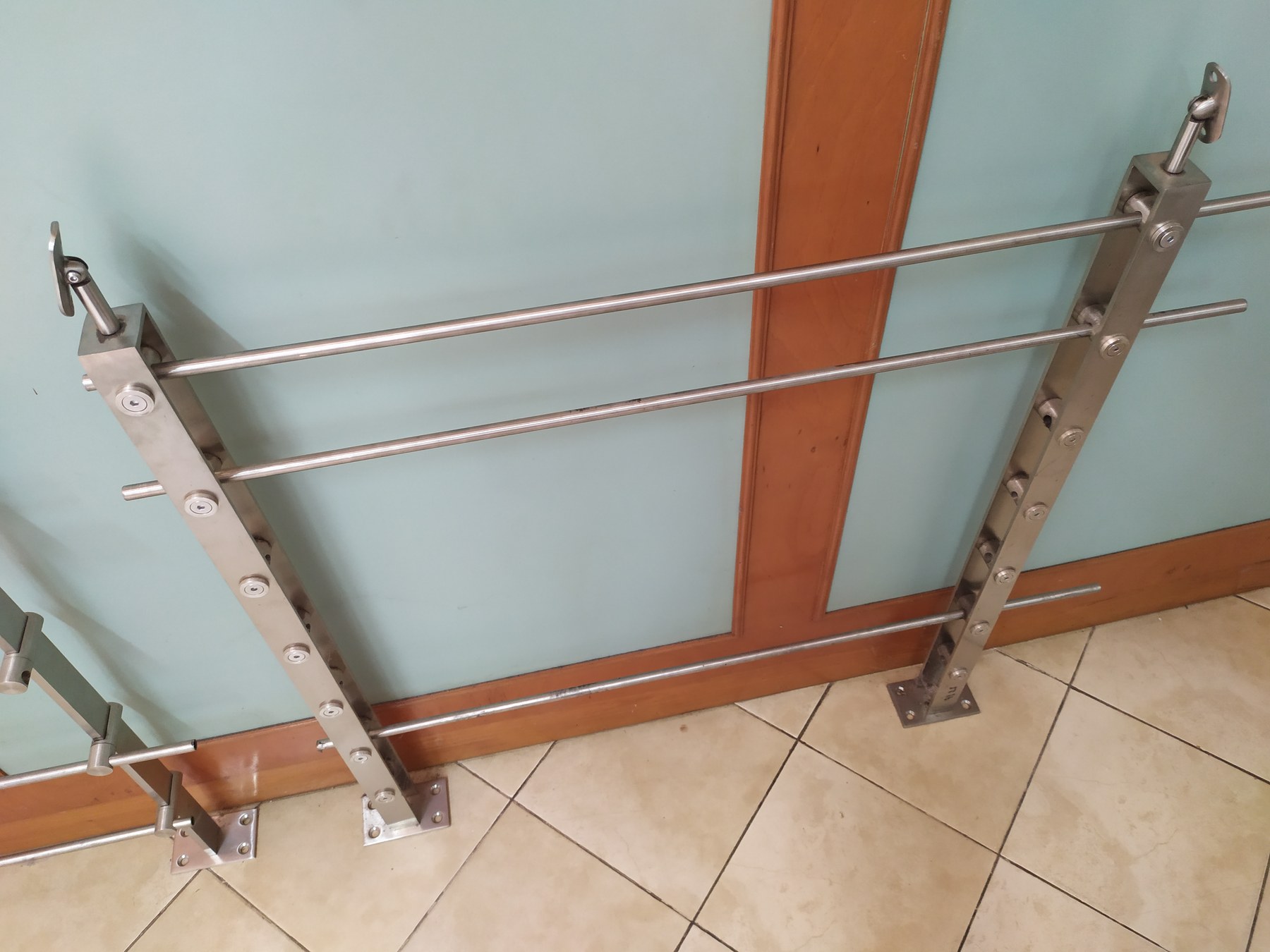 Baranda de acero inoxidable con las placas base atornilladas al piso a la vista · MÁS VIDRIOS