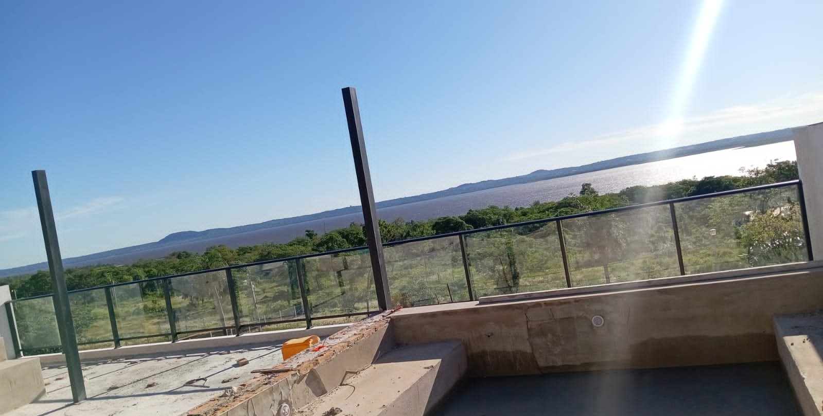 Baranda de vidrio y aluminio negro cerrando una terraza con piscina en obra · MÁS VIDRIOS