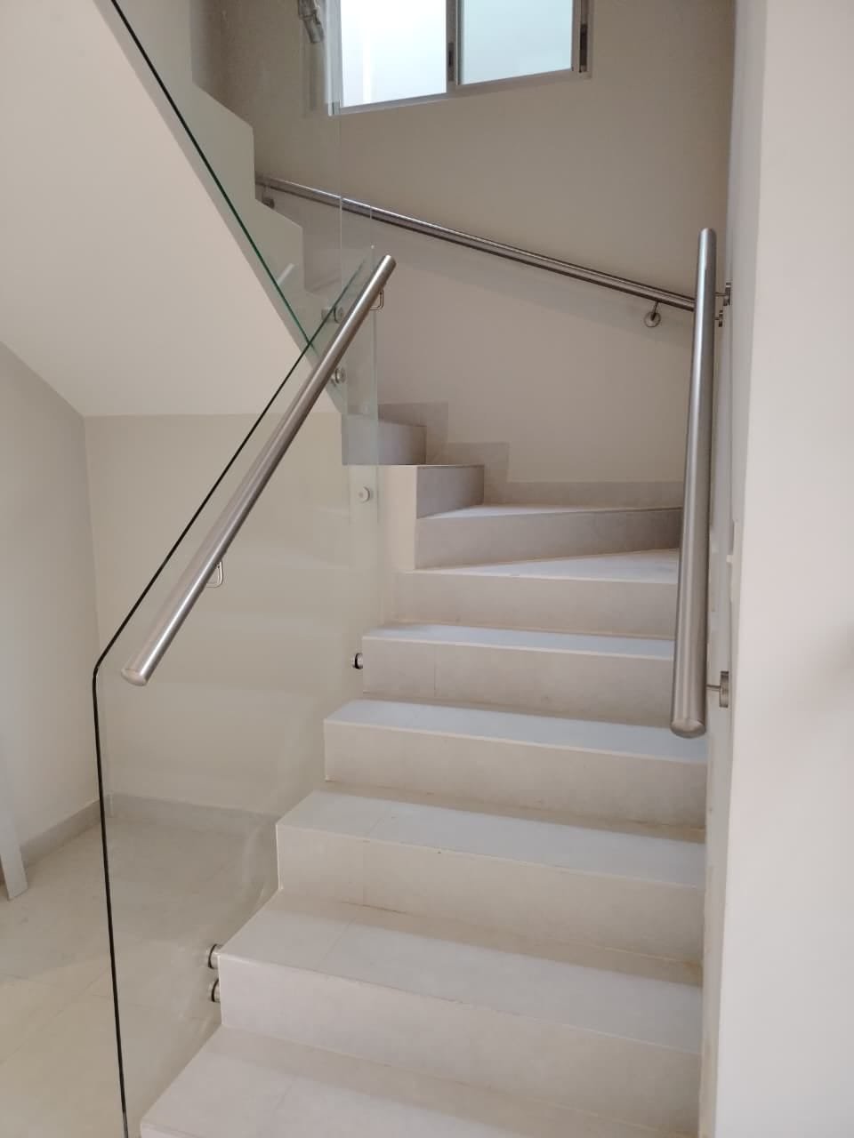 Baranda de vidrio con pasamanos de acero inoxidable en escalera residencial · MÁS VIDRIOS