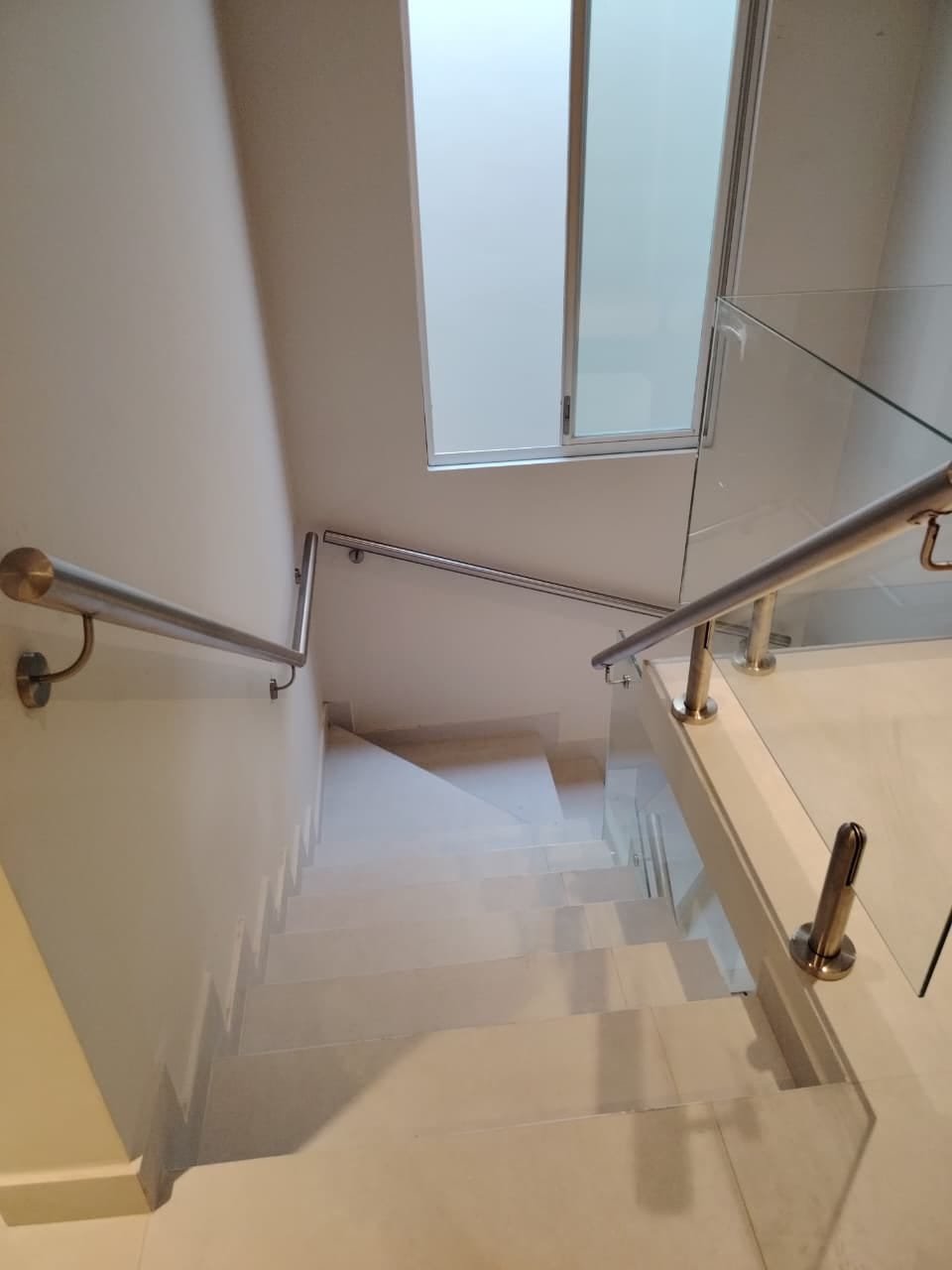 Escalera con pasamanos de acero inoxidable y baranda de vidrio en vivienda · MÁS VIDRIOS