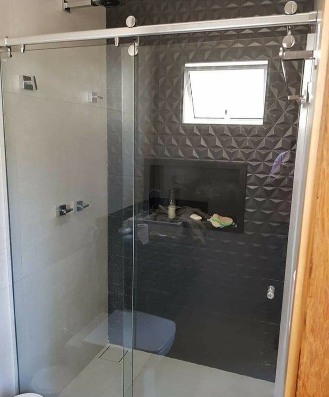 Box de ducha corredizo con herrajes cromados en baño con pared texturada · MÁS VIDRIOS