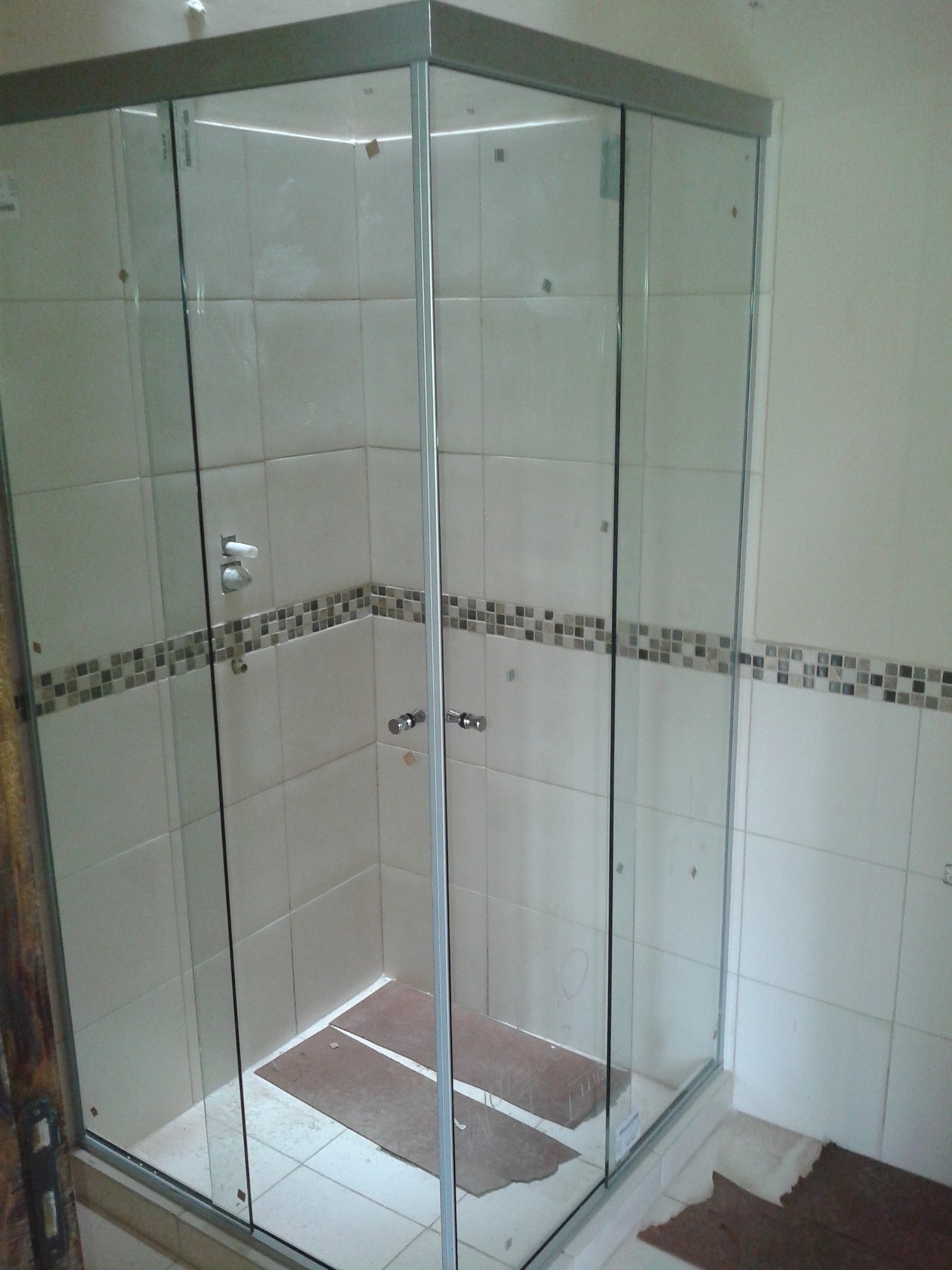 Box de ducha esquinero de vidrio con perfilería de aluminio en baño con cenefa de mosaico · MÁS VIDRIOS
