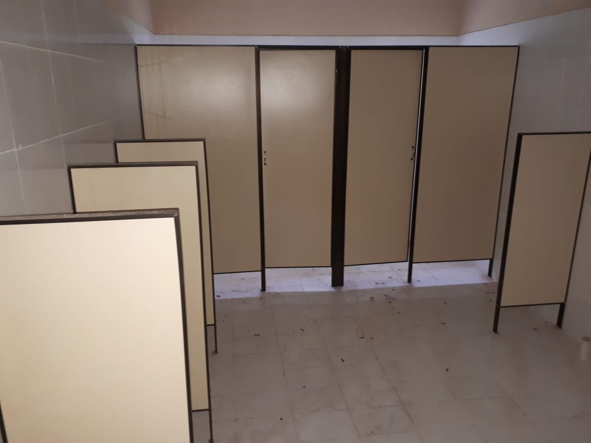 Cabinas de sanitario en Eucatex beige con estructura negra, montaje en obra · MÁS VIDRIOS