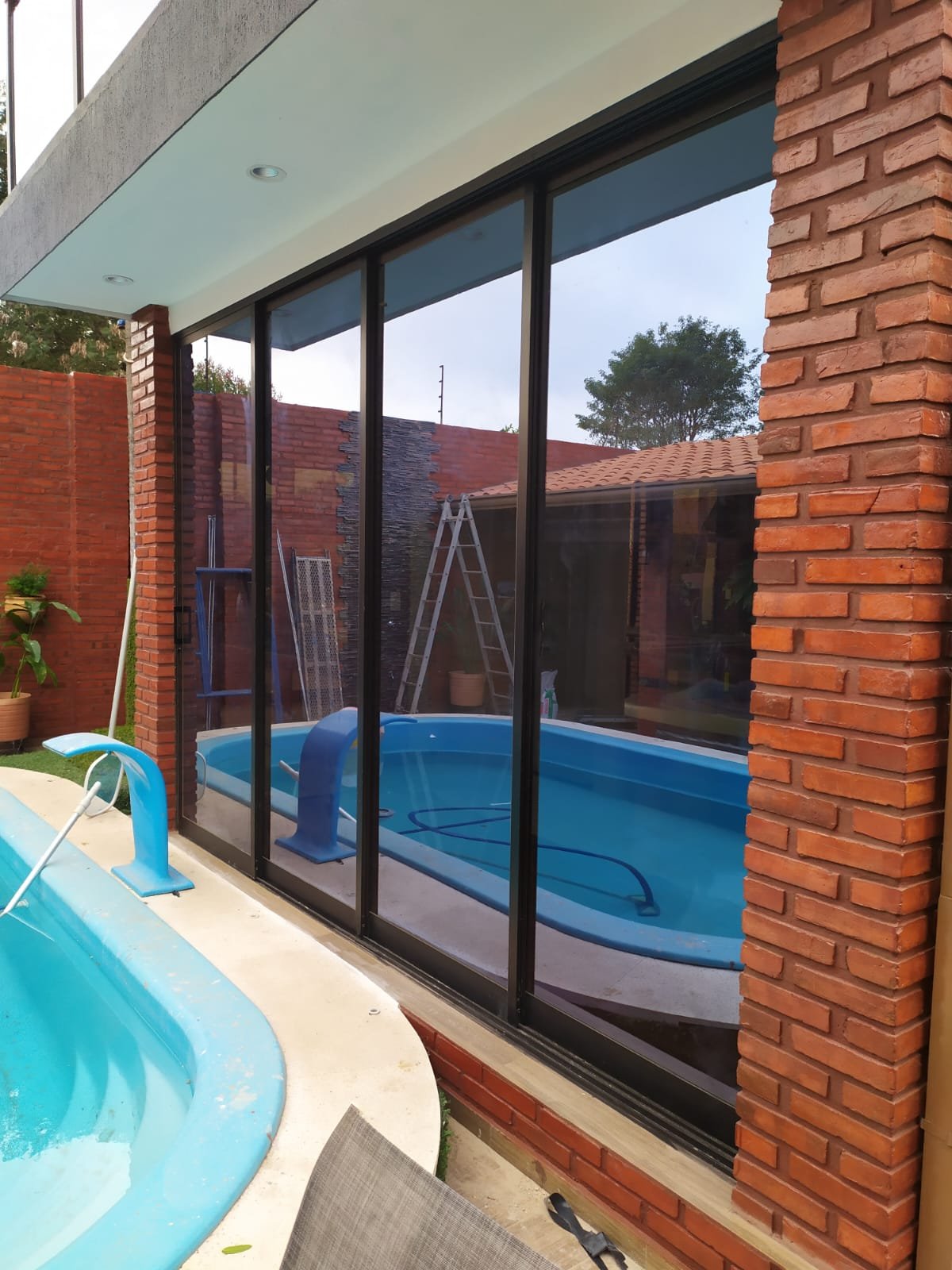 Cerramiento de vidrio con perfiles de aluminio negro junto a piscina · MÁS VIDRIOS