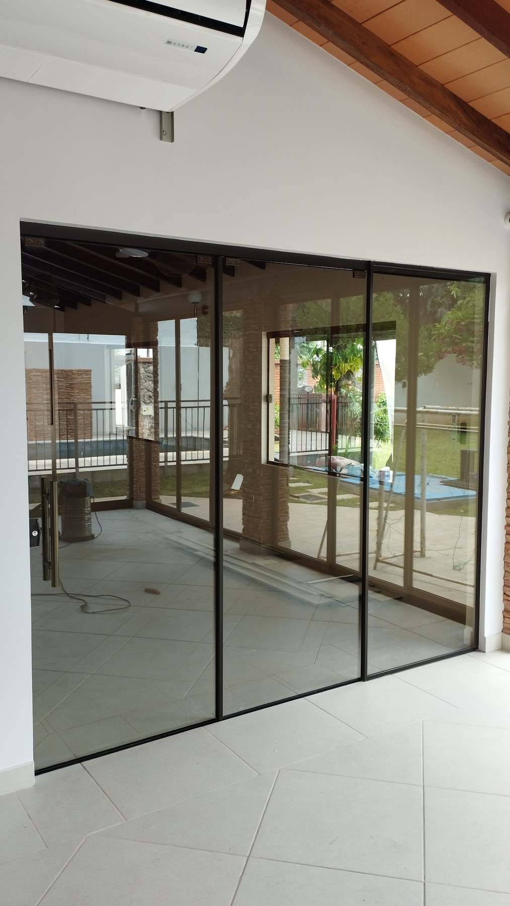 Puerta corrediza de aluminio negro con paños fijos hacia el jardín · MÁS VIDRIOS