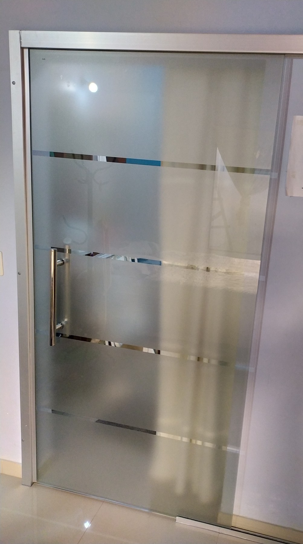 Puerta corrediza de vidrio ploteado con franjas transparentes y tirador de acero · MÁS VIDRIOS