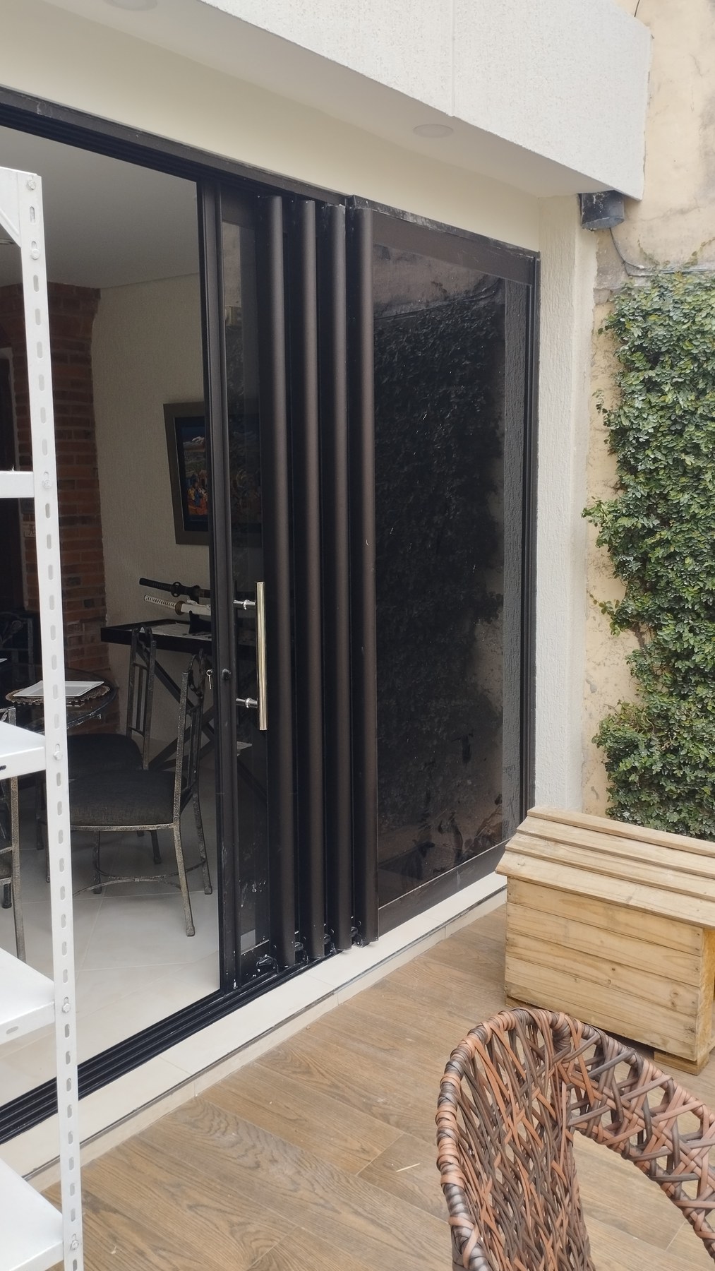 Puerta corrediza de aluminio negro con vidrio hacia galería con deck de madera · MÁS VIDRIOS