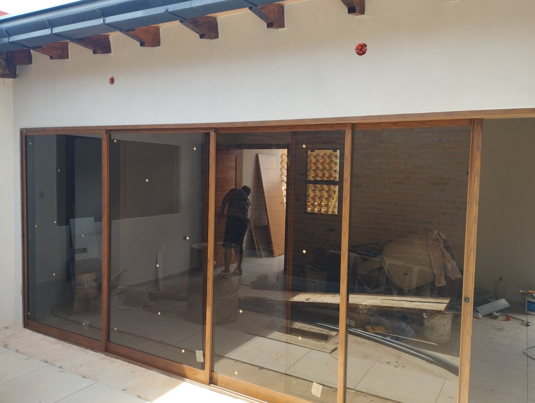 Puertas corredizas de aluminio símil madera con vidrio bajo galería con vigas de madera · MÁS VIDRIOS