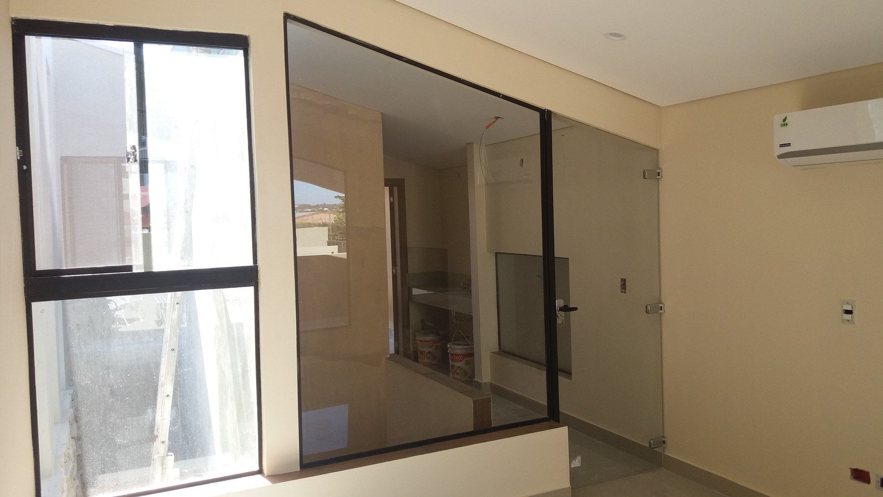 División de vidrio con perfilería de aluminio negra y puerta batiente en living · MÁS VIDRIOS