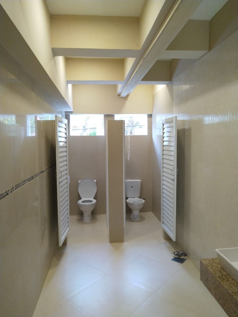 División de sanitarios con puertas de celosía de aluminio blanco · MÁS VIDRIOS