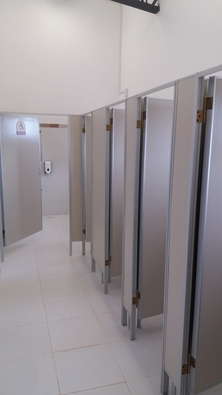 Cabinas de sanitario en Eucatex con perfilería de aluminio en un baño público · MÁS VIDRIOS