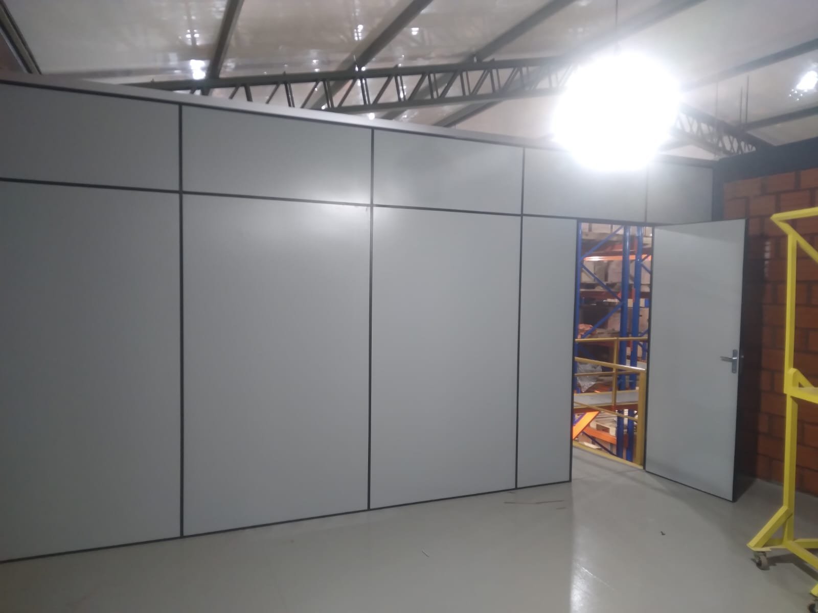 Divisoria de Eucatex gris con puerta cerrando un sector de depósito · MÁS VIDRIOS