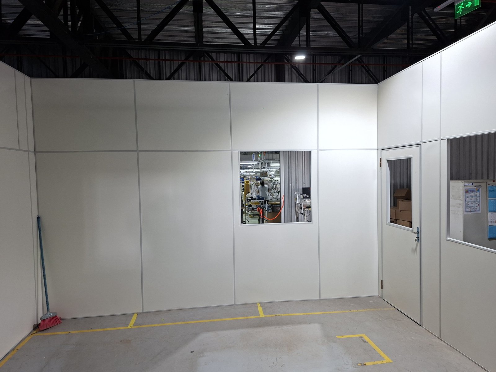 Divisoria de oficina en Eucatex blanco con puerta y ventanas dentro de una planta industrial · MÁS VIDRIOS