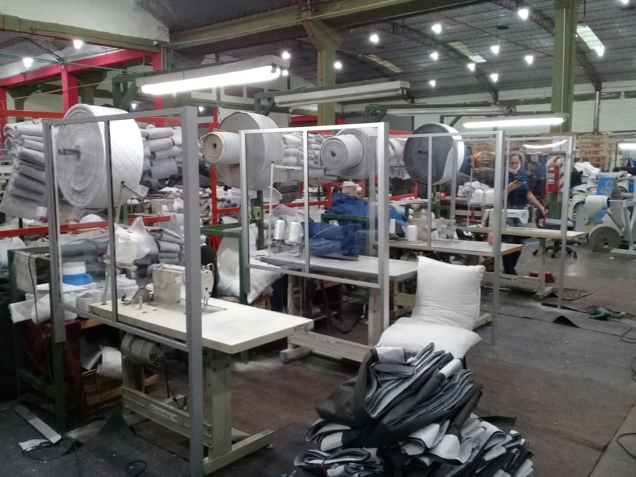 Divisorias de acrílico con marco de aluminio entre puestos de costura de un taller textil · MÁS VIDRIOS