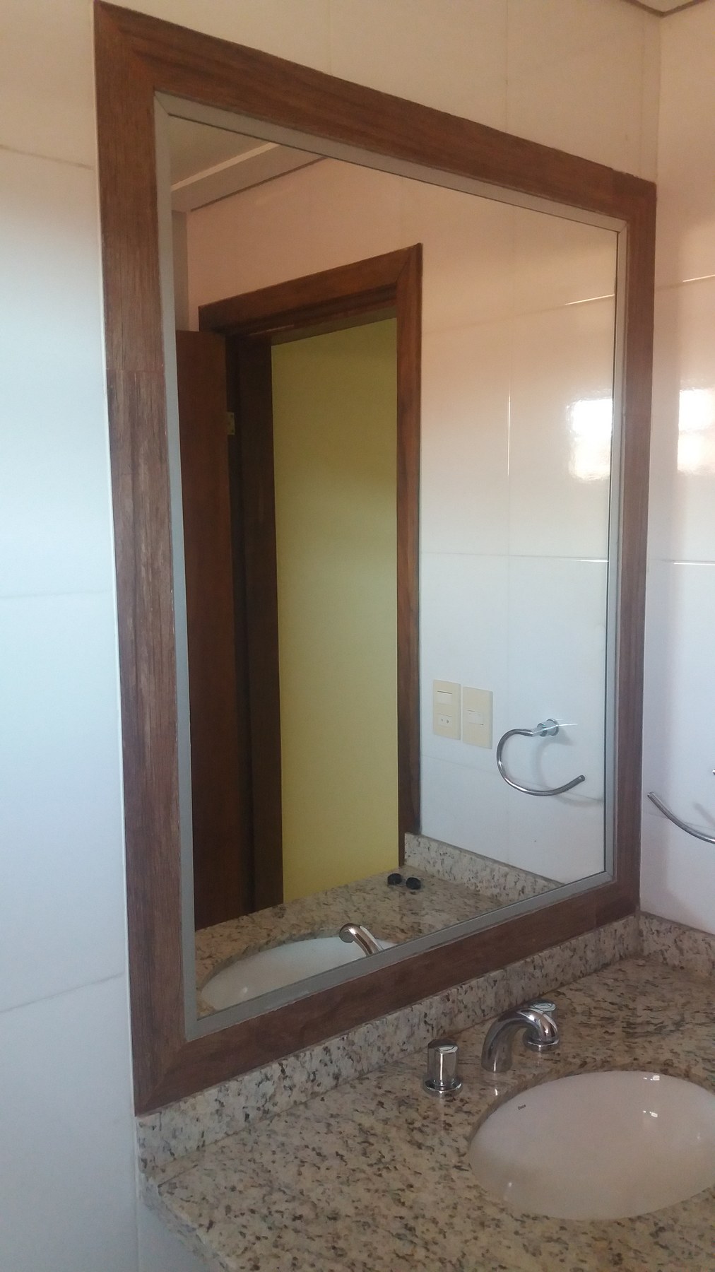 Espejo con marco de madera sobre mesada de granito en baño · MÁS VIDRIOS