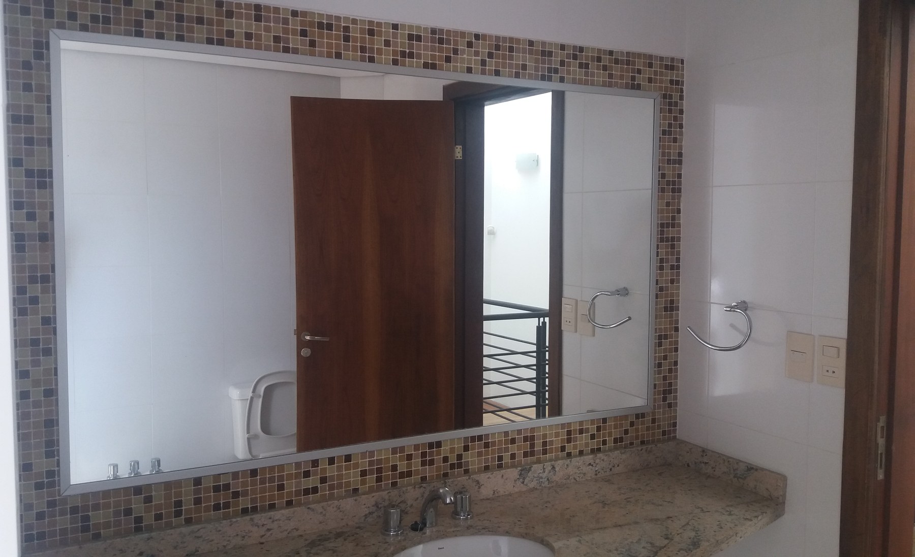 Espejo rectangular enmarcado con mosaico veneciano sobre mesada de granito · MÁS VIDRIOS