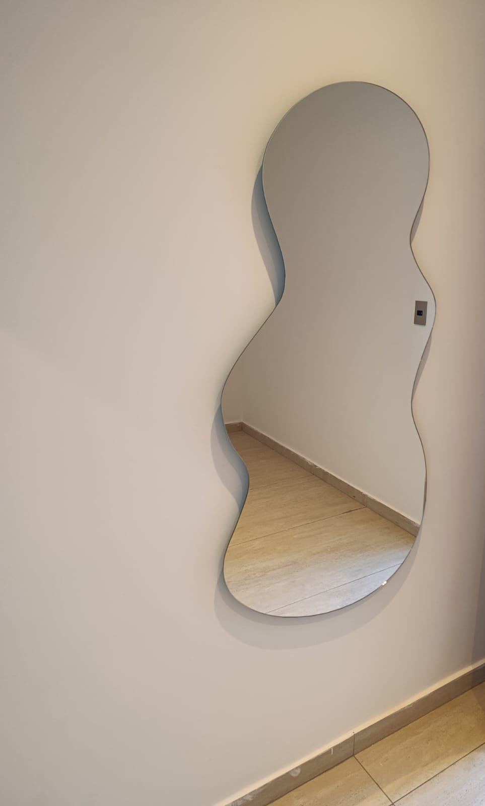 Espejo decorativo de forma orgánica sin marco instalado en pared interior de vivienda · MÁS VIDRIOS