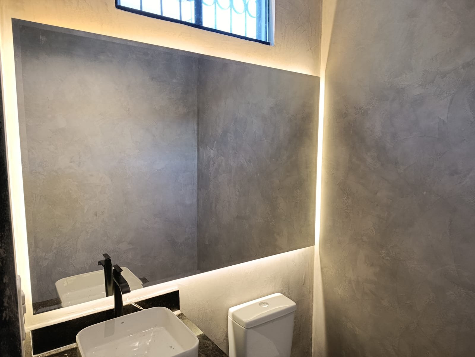 Espejo retroiluminado con LED sobre mesada de granito en baño moderno · MÁS VIDRIOS
