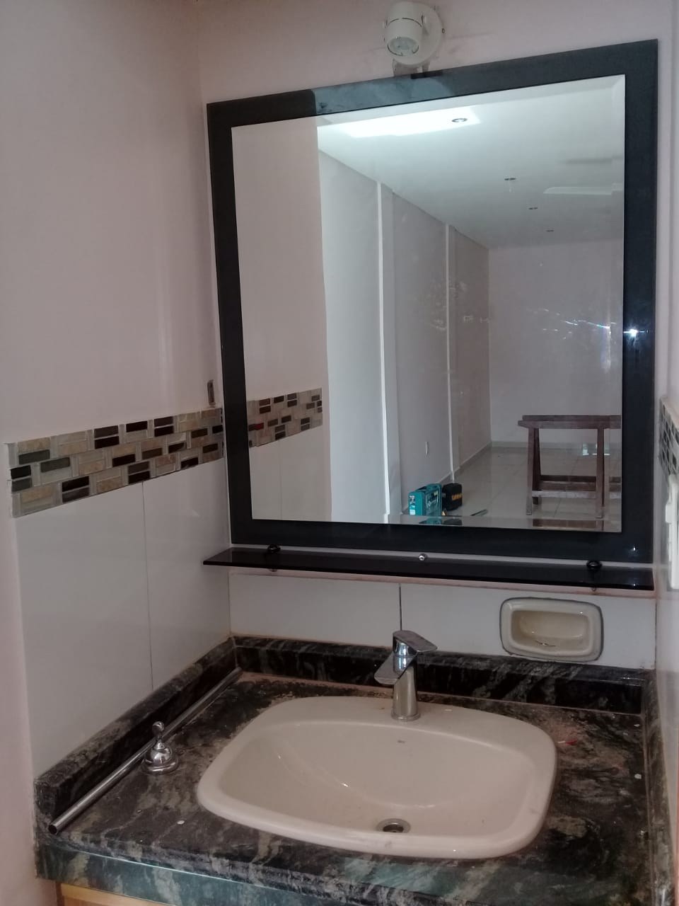 Espejo de baño sobre panel de vidrio oscuro con repisa de vidrio · MÁS VIDRIOS