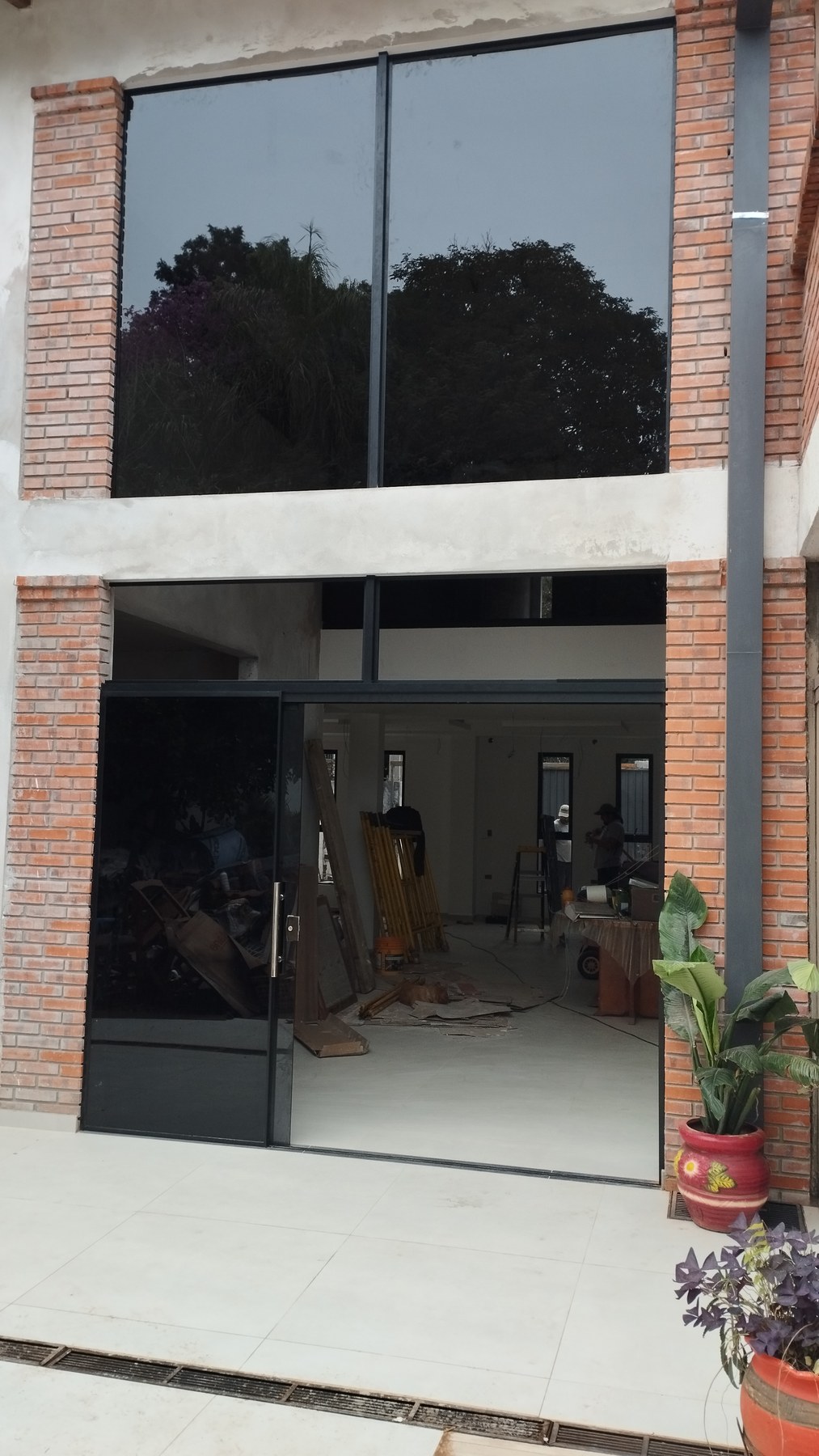 Fachada de ladrillo con paños de vidrio y puerta corrediza de aluminio en doble altura · MÁS VIDRIOS