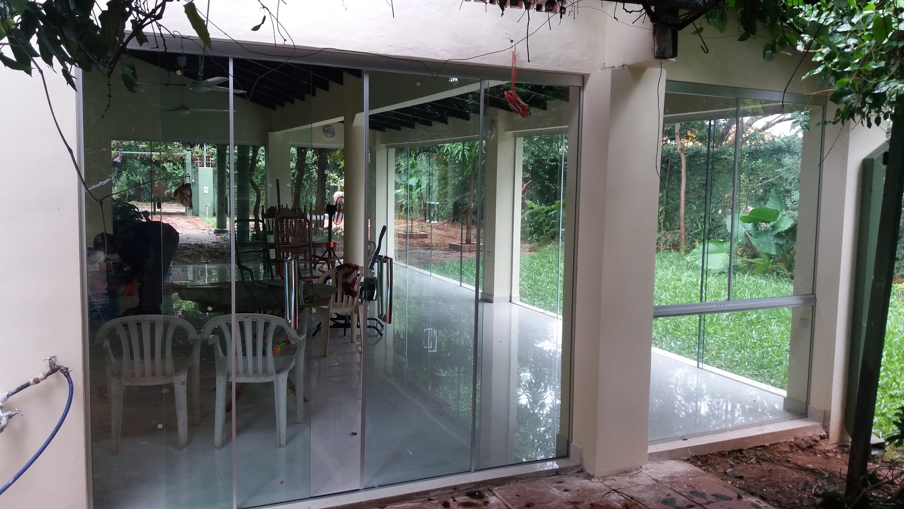 Cerramiento de galería con paños de vidrio sin marco visto desde el jardín · MÁS VIDRIOS