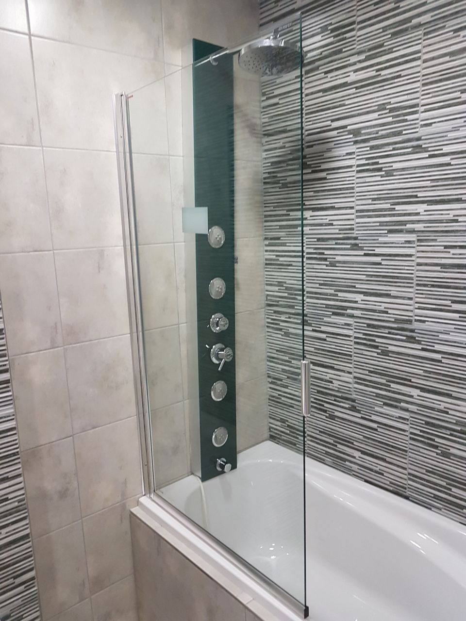 Mampara de vidrio sobre bañera con columna de ducha en baño terminado · MÁS VIDRIOS