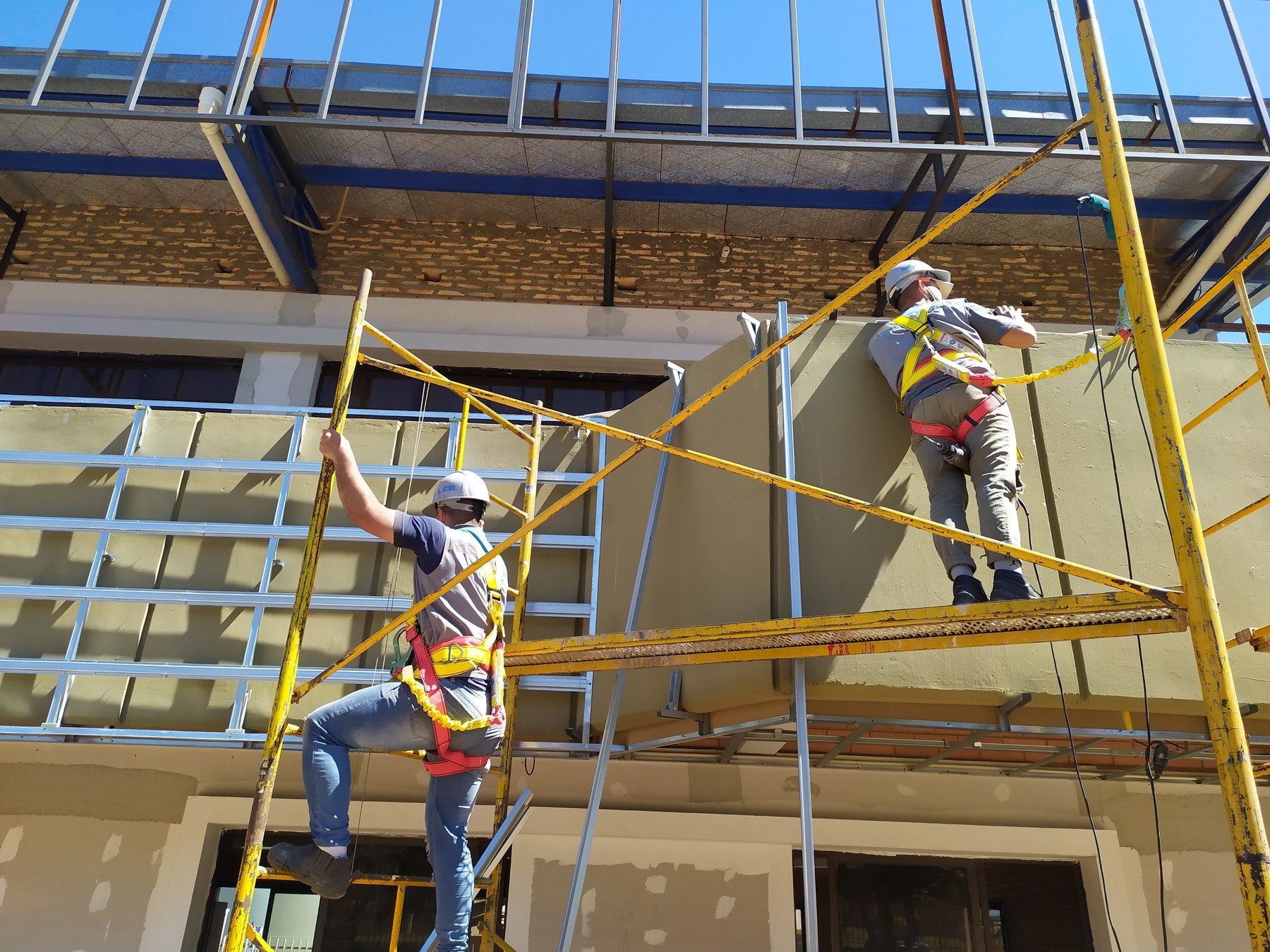 Dos operarios montando el revestimiento de placa cementicia en una fachada · MÁS VIDRIOS