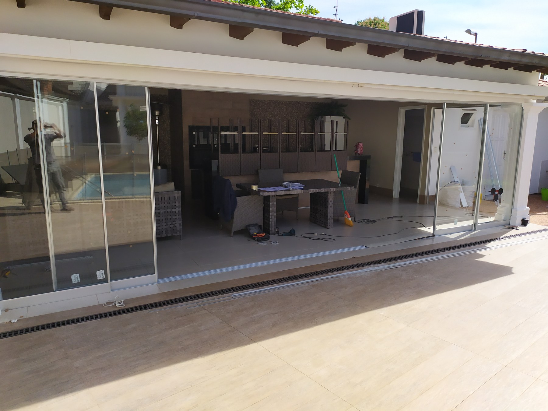 Paneles corredizos Novaslider abiertos y apilados a un costado en galería de quincho · MÁS VIDRIOS
