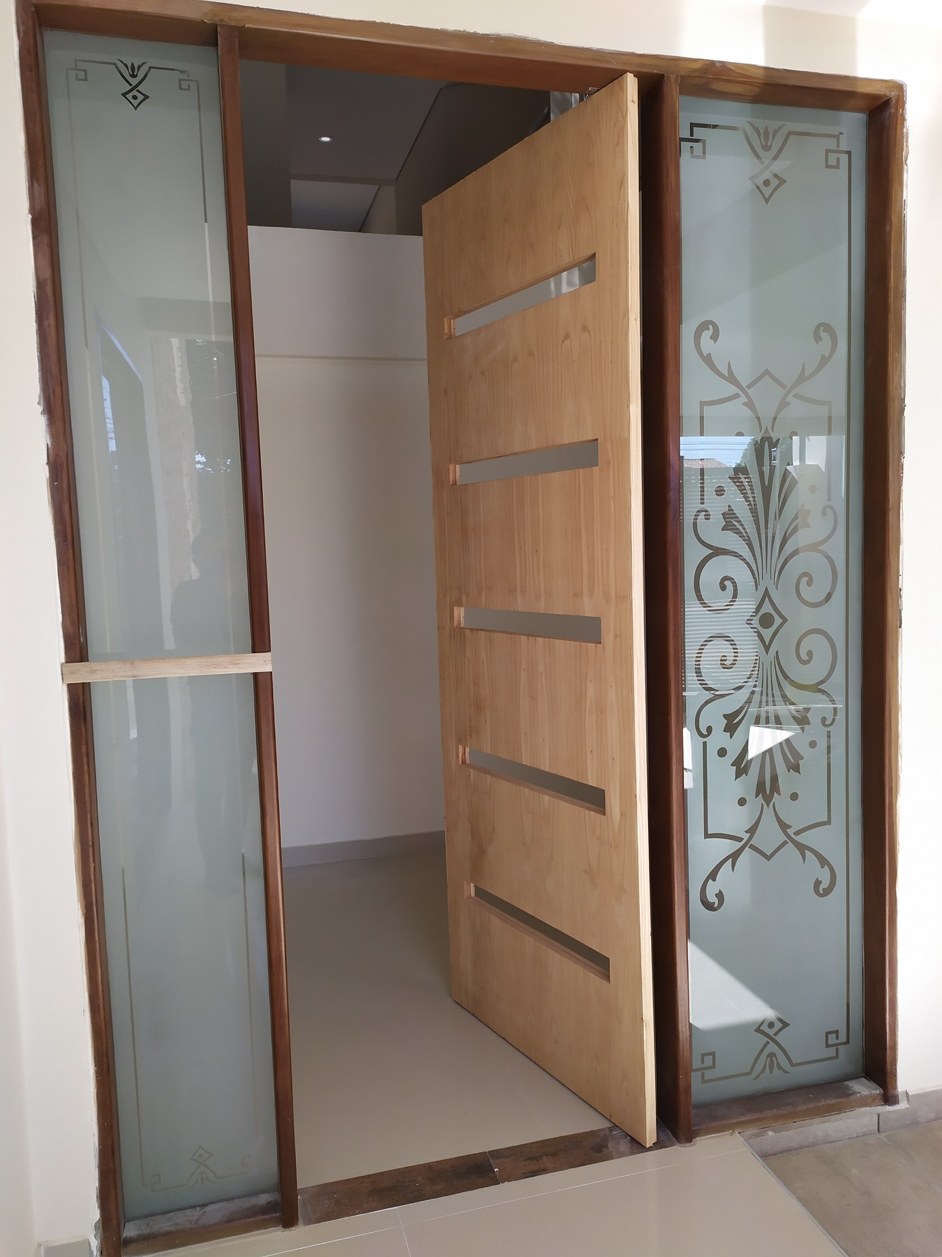 Puerta de entrada con paños laterales de vidrio ploteado con diseño clásico · MÁS VIDRIOS