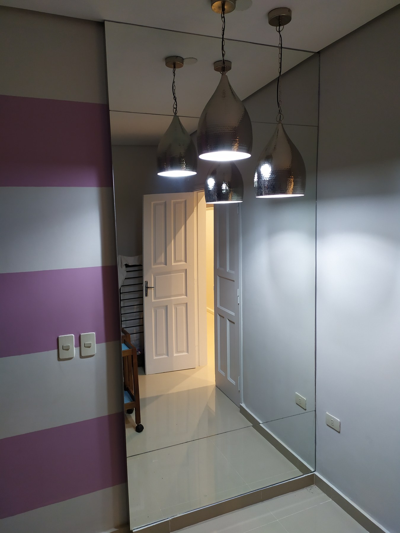 Pared revestida en espejo en comedor, con el reflejo de las lámparas colgantes · MÁS VIDRIOS