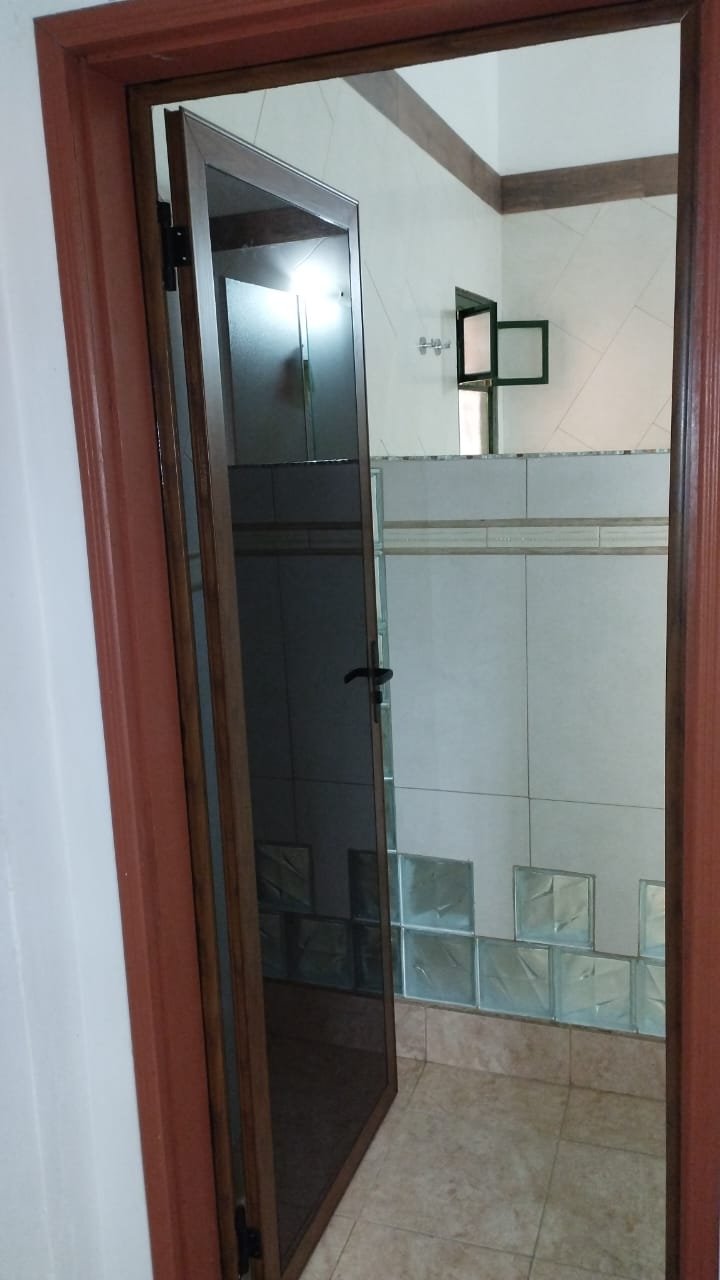 Puerta de aluminio símil madera con vidrio tonalizado y bloques de vidrio en baño · MÁS VIDRIOS