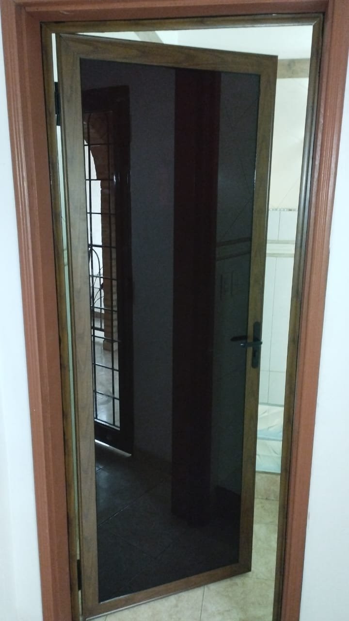 Puerta de aluminio símil madera con vidrio fumé para baño · MÁS VIDRIOS