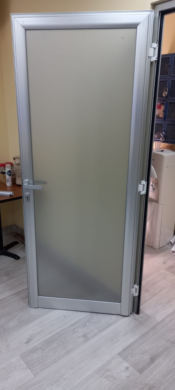 Puerta batiente de aluminio con paño de vidrio ploteado en interior de oficina · MÁS VIDRIOS