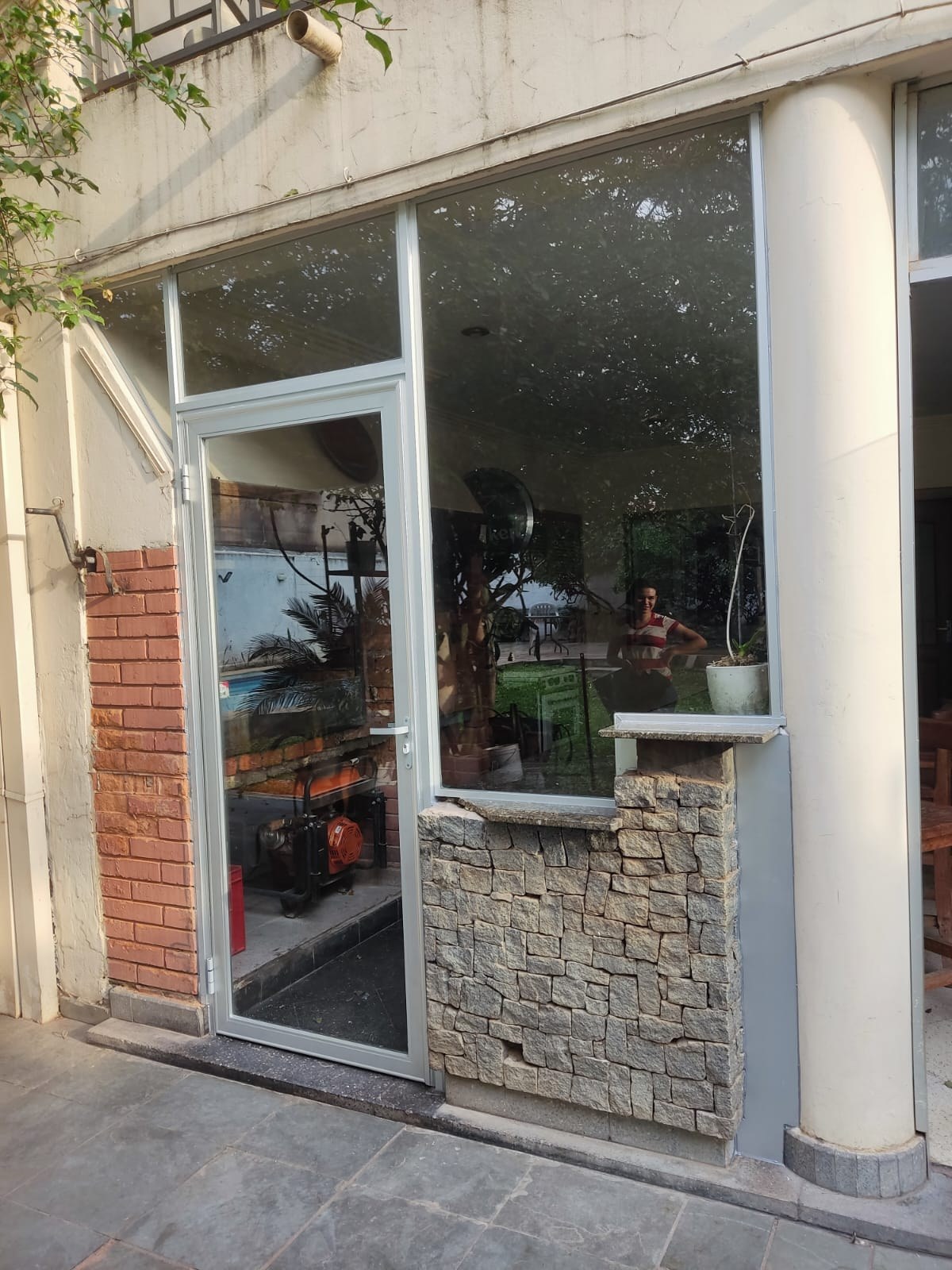 Puerta batiente de aluminio blanco con paño fijo vidriado en frente de local · MÁS VIDRIOS