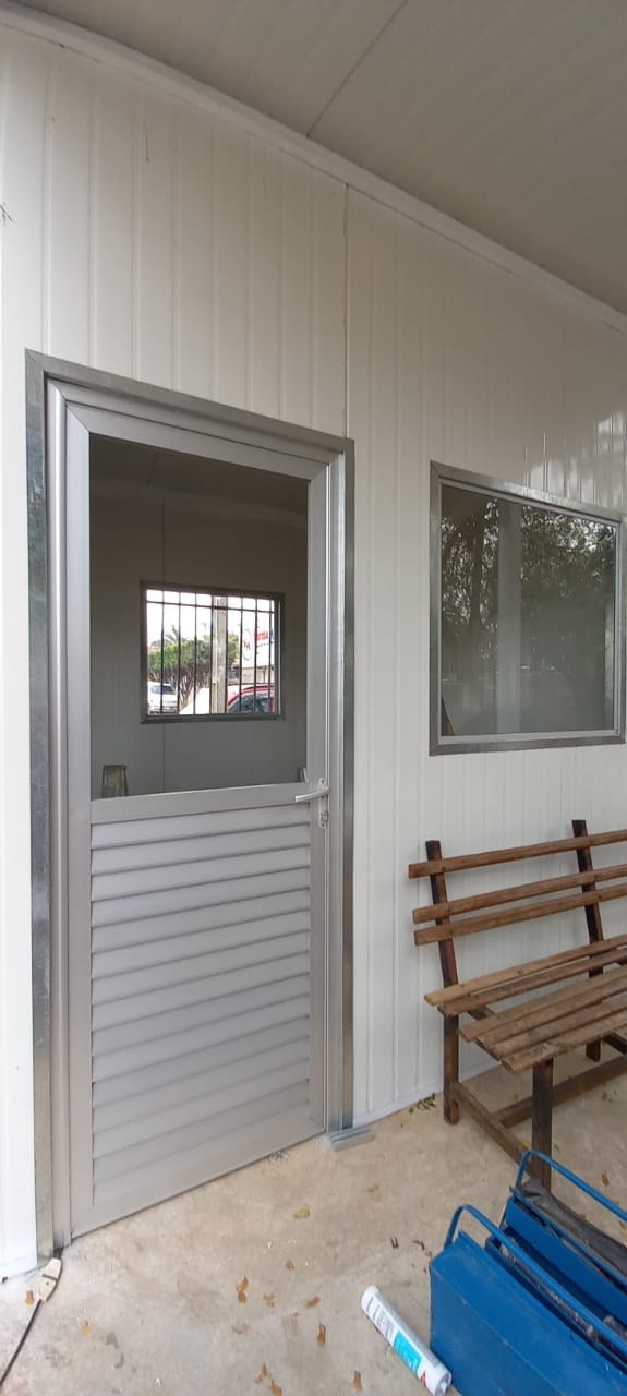 Puerta batiente de aluminio con paño de vidrio y celosía baja en módulo de paneles blancos · MÁS VIDRIOS