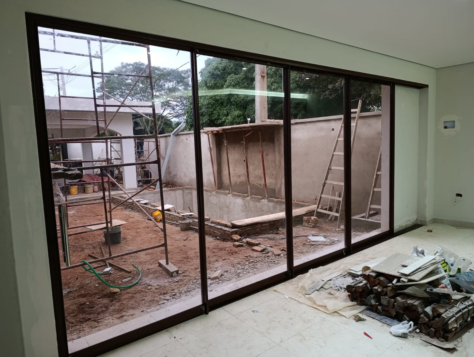 Puerta corrediza de aluminio de cuatro hojas con vidrio de piso a techo en vivienda en construcción · MÁS VIDRIOS