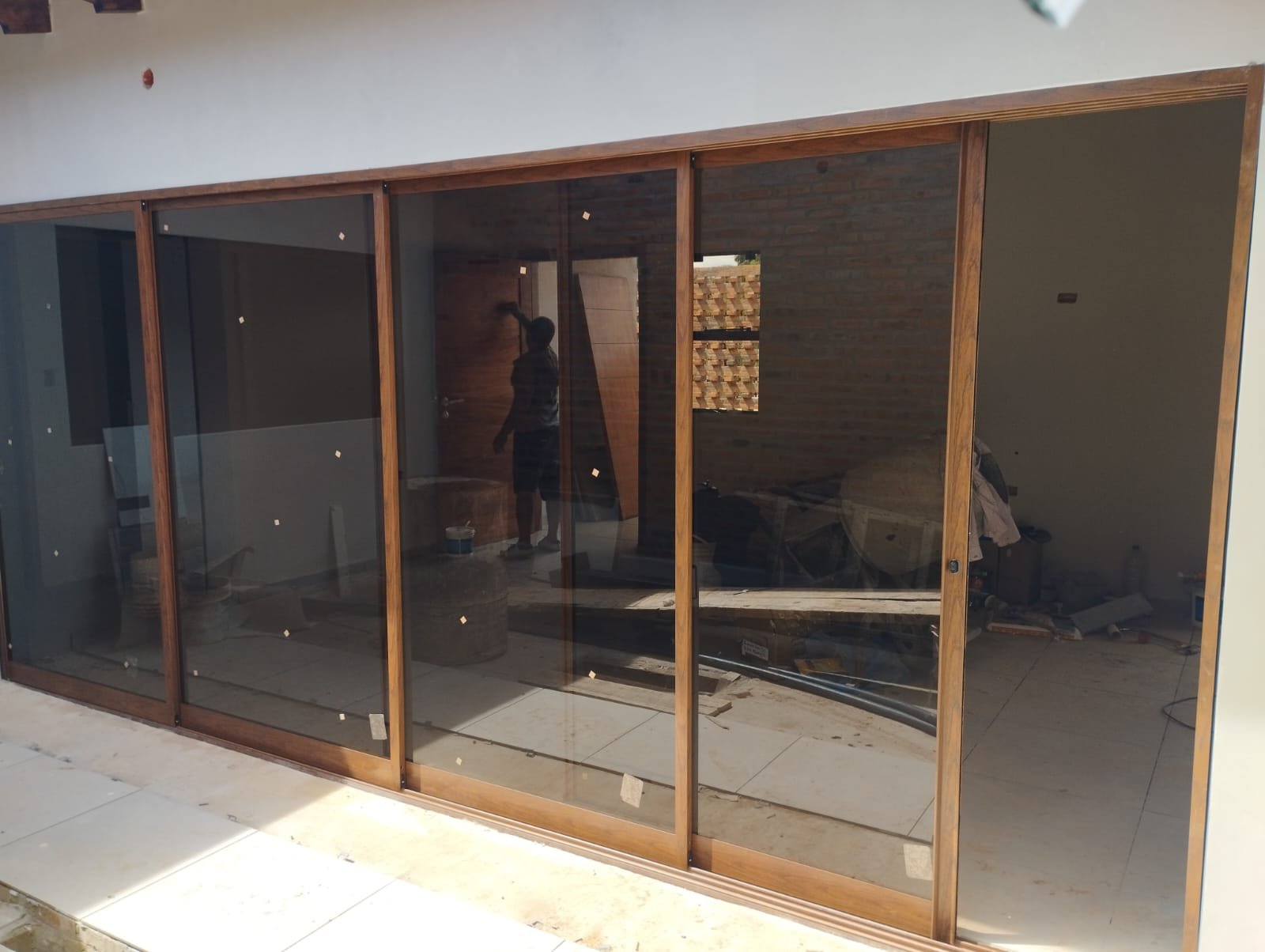 Puerta corrediza de aluminio símil madera con vidrio bronce en obra residencial · MÁS VIDRIOS