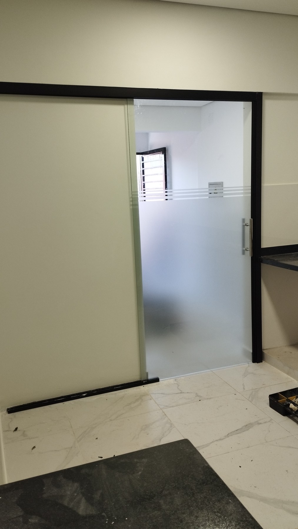 Puerta corrediza de vidrio ploteado con riel a la vista en interior · MÁS VIDRIOS