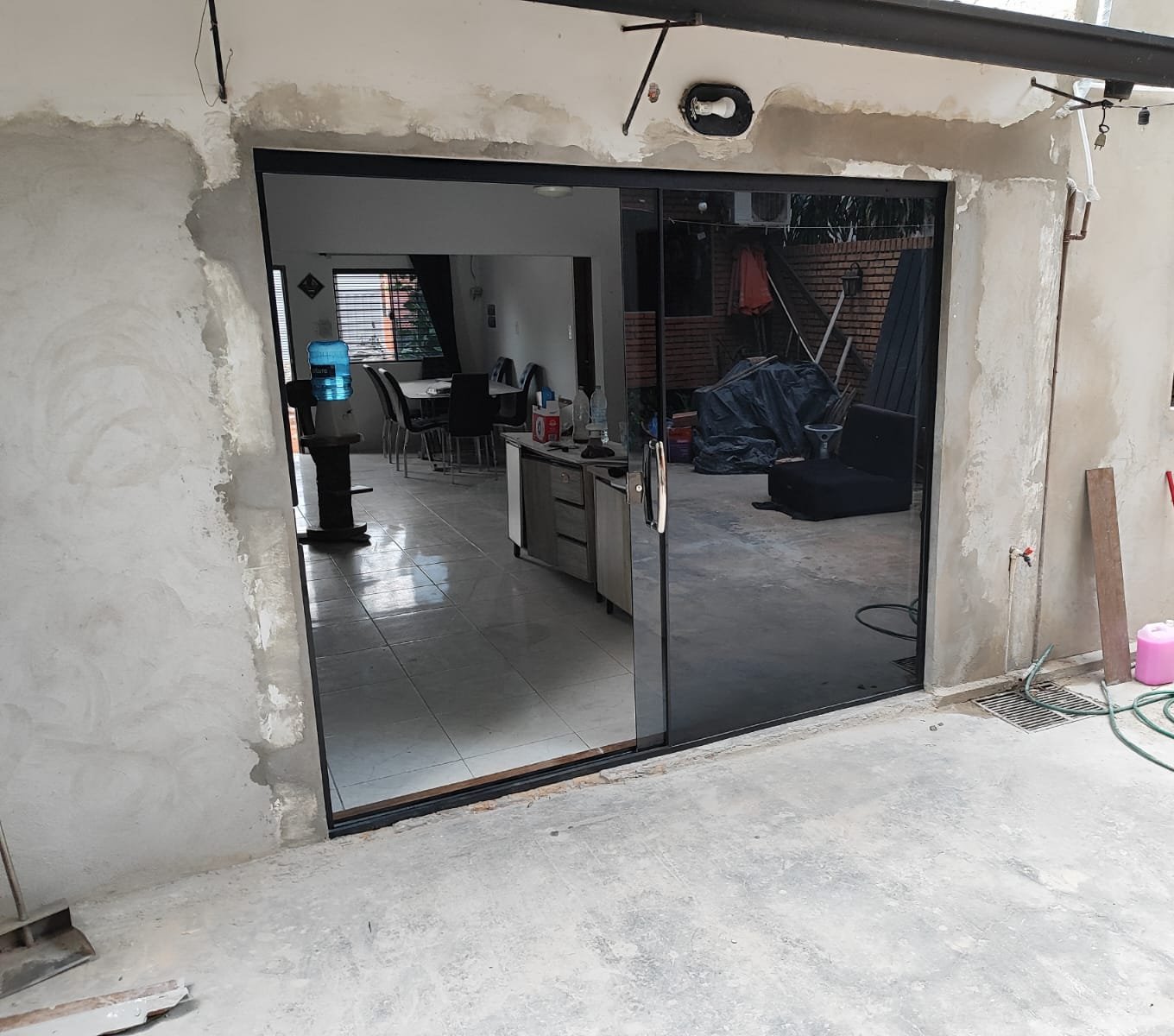 Puerta corrediza de vidrio templado fumé con perfiles negros en vivienda · MÁS VIDRIOS