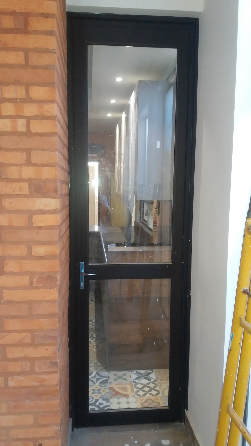 Puerta de aluminio negro con paño de vidrio entero en acceso de pared de ladrillo visto · MÁS VIDRIOS