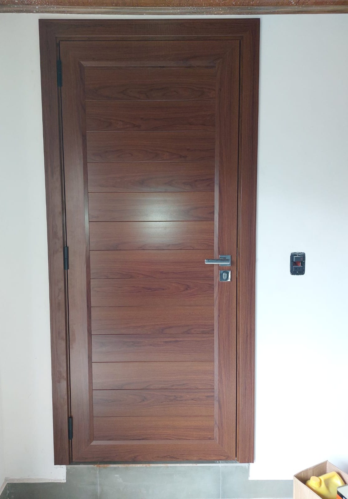 Puerta batiente de aluminio símil madera con tablero ranurado en ambiente interior · MÁS VIDRIOS