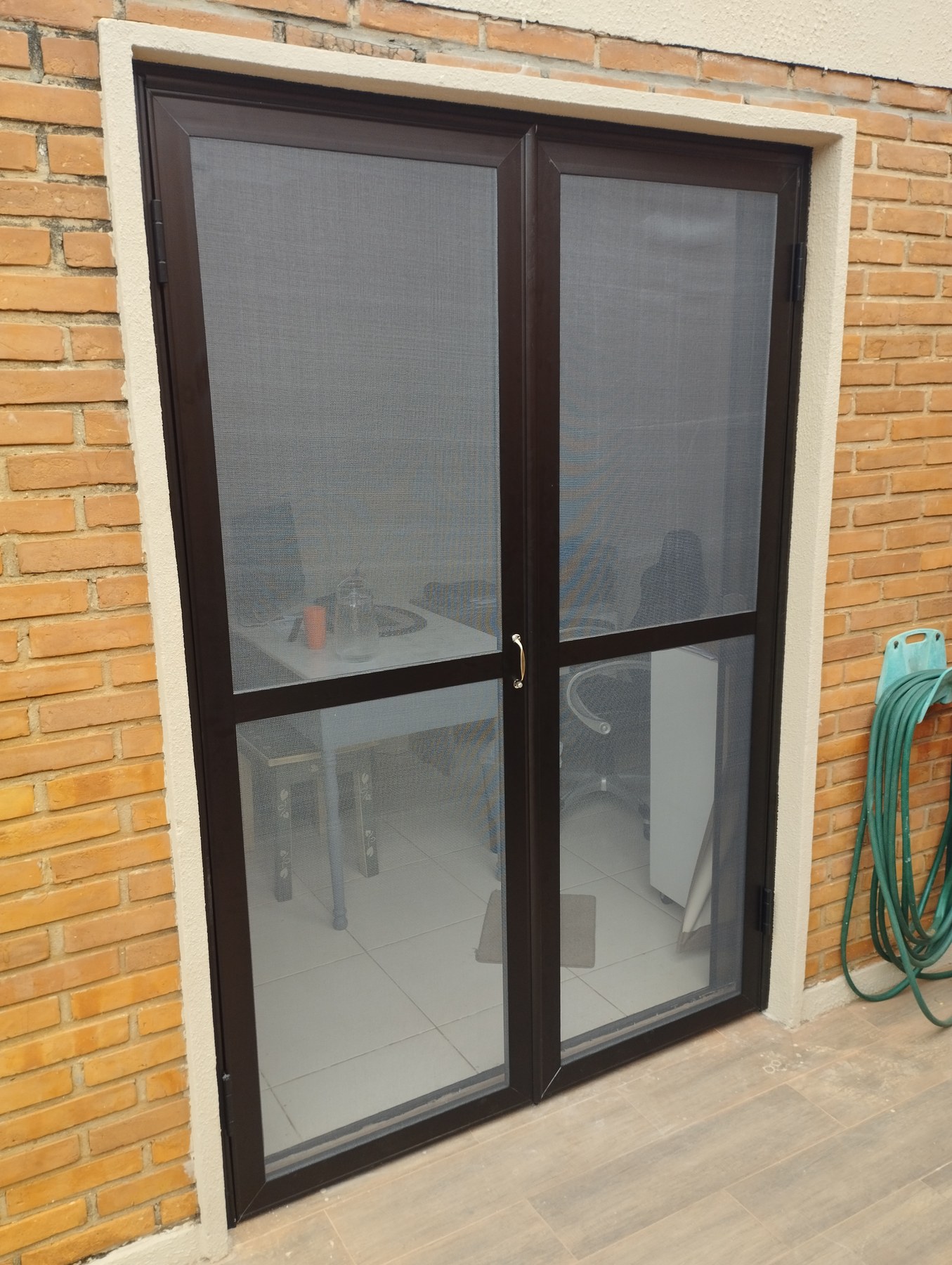 Puerta mosquitero de dos hojas con perfilería marrón en el acceso a un comedor · MÁS VIDRIOS