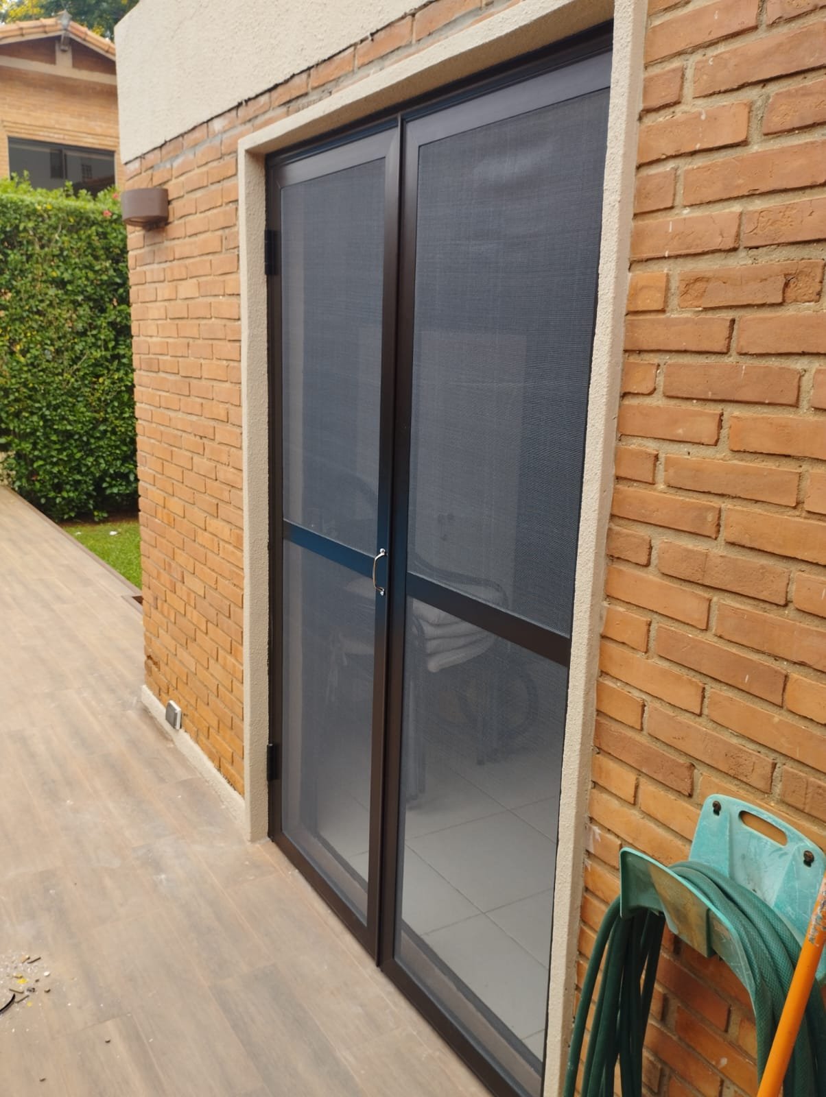 Puerta mosquitero doble de aluminio en patio de vivienda · MÁS VIDRIOS