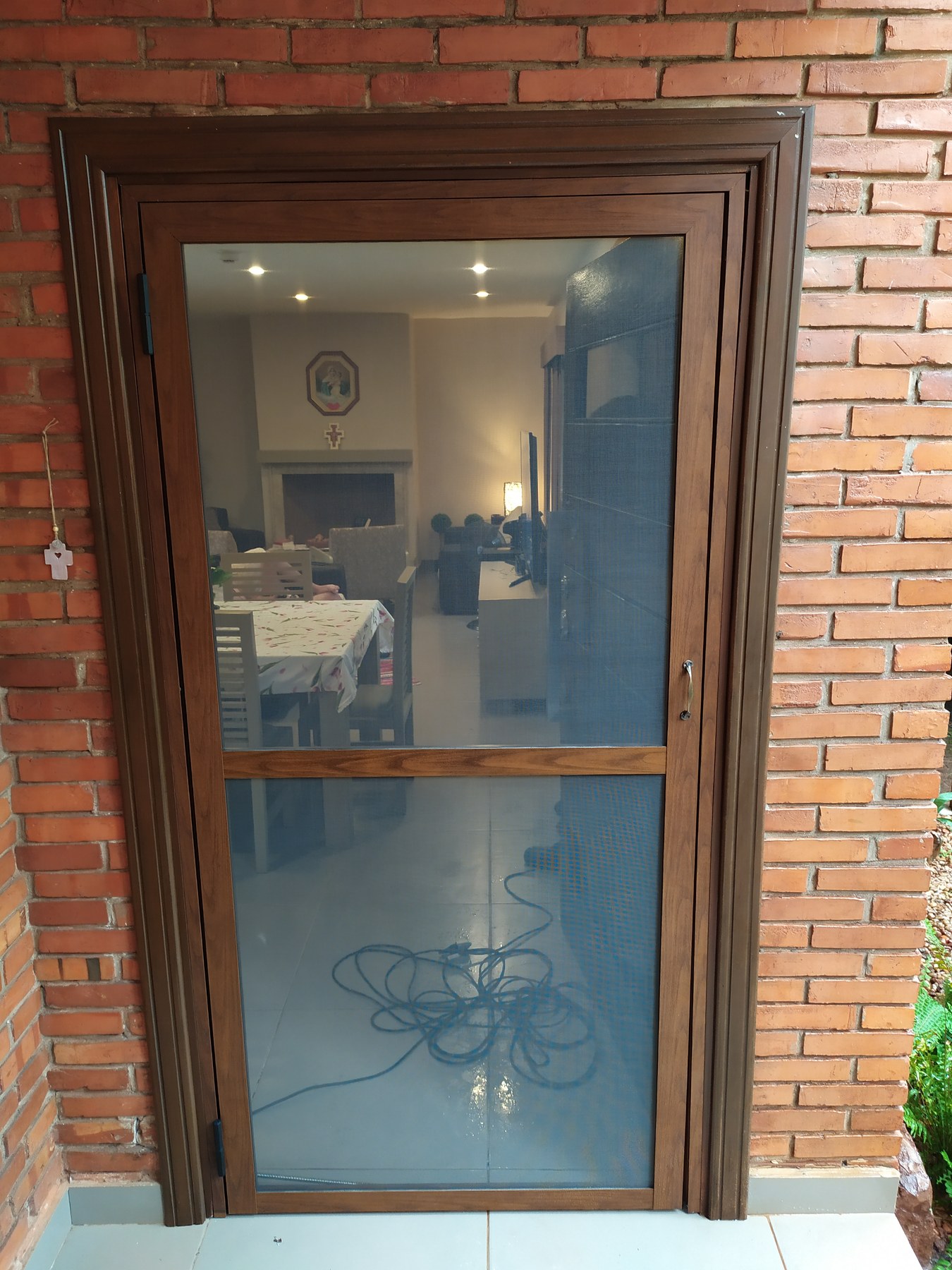 Puerta de aluminio símil madera con mosquitero en pared de ladrillo visto · MÁS VIDRIOS