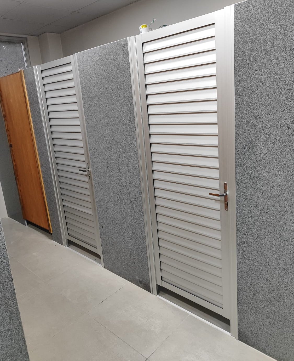 Puertas de celosía de aluminio en sanitarios de local comercial · MÁS VIDRIOS