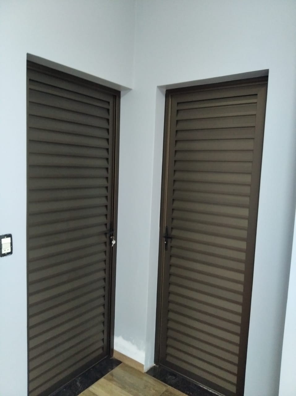 Puertas batientes de celosía completa en aluminio color bronce en ambiente interior · MÁS VIDRIOS