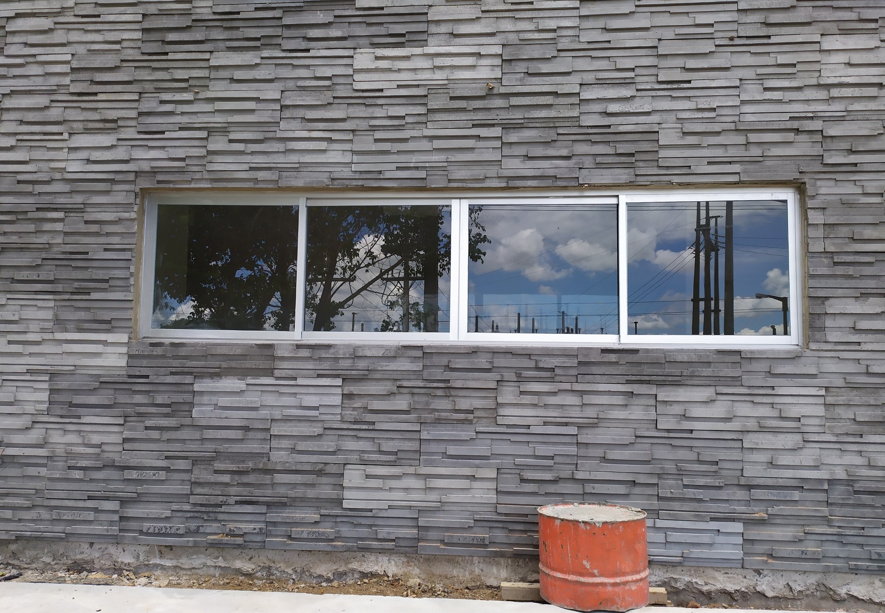 Ventana corrediza de aluminio blanco de varias hojas sobre revestimiento de piedra · MÁS VIDRIOS