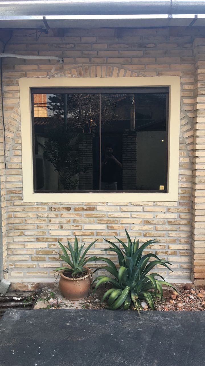 Ventana corrediza con marco claro y vidrio oscuro en pared de ladrillo visto · MÁS VIDRIOS